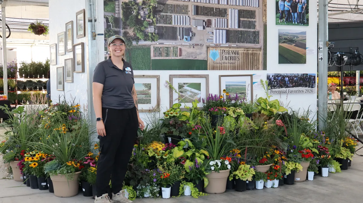 Macahl standing beside a display of perennials in front of the framed Perennial Favorites photo wall