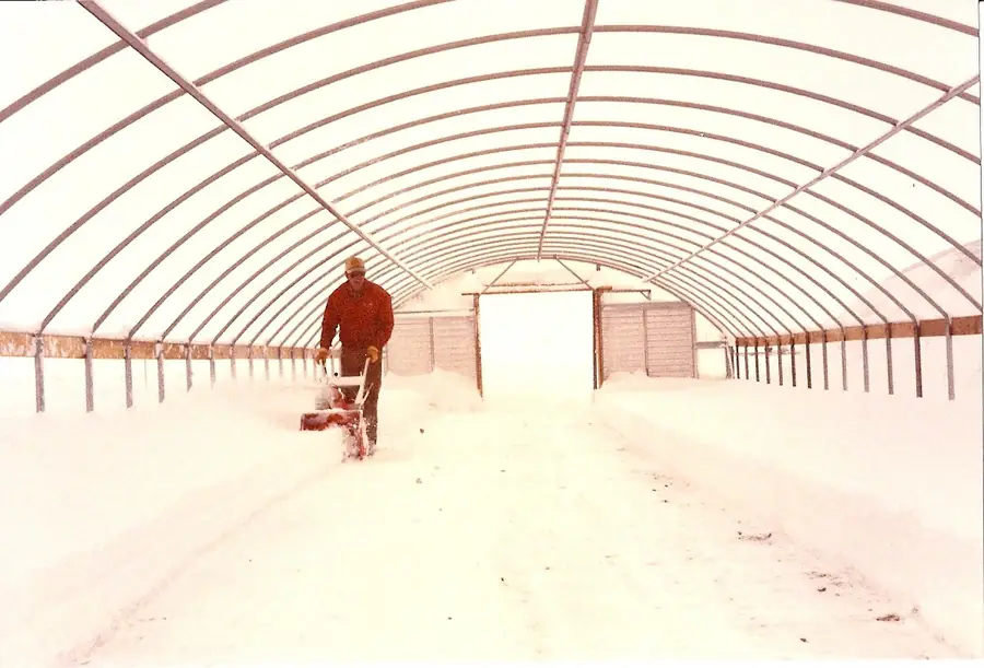 Preston Cox clearing snow inside the first greenhouse