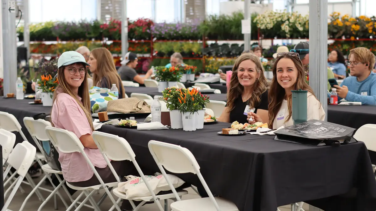 Guests smiling at a lunch table with racks of flowers behind