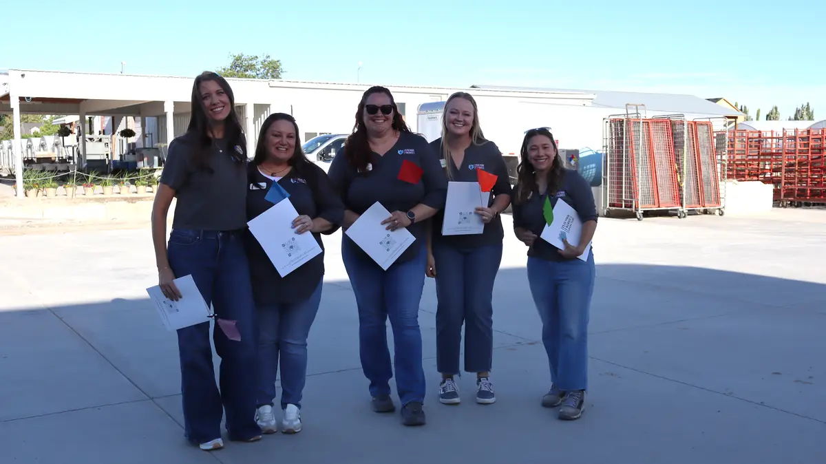 Five PF team members smiling in the yard with event programs
